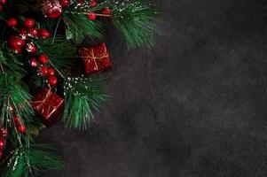 Top view on fir tree branches and gift boxes on dark background. Banner with place for text.Christmas background photo