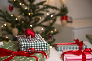 Pile of christmas presents on the table near xmas tree. FEstive background with place for text photo