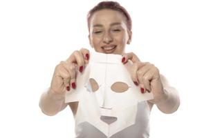 tratamientos faciales y de belleza. mujer con una mascarilla hidratante en la cara aislada de fondo blanco foto