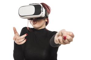 linda mujer emocionada con auriculares vr mirando hacia arriba y tratando de tocar objetos en la realidad virtual foto