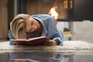 Blonde women by a fire place reading a book. life stile concept