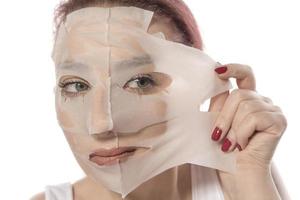 Face care and beauty treatments. Woman with a sheet moisturizing mask on her face isolated on white background photo