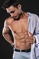 guapo modelo árabe masculino con cuerpo perfecto posando en el estudio. retrato de un modelo masculino atlético posando sobre fondo oscuro en el estudio. concepto de moda. foto