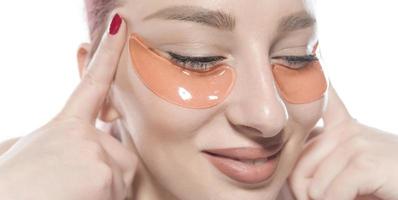 woman with cosmetic patches moisturizing on skin under eyes. photo