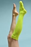 Woman with beautiful legs wears green socks on her feet. Isolated on blue background photo