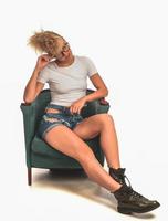 fashionable stylish crazy blond woman siting in the chair and posing in front of camera in studio. fashion beauty concept photo