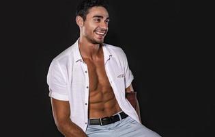 Handsome Arab male model with perfect body posing in studio. Portrait of a athletic male model posing on dark background in the studio. Fashion concept. photo