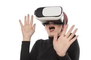 Pretty cute excited female in VR headset looking up and trying to touch objects in virtual reality photo