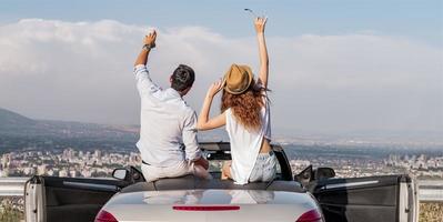 feliz pareja joven divirtiéndose en un auto convertible en un hermoso día de verano foto