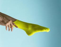 Woman with beautiful legs wears green socks on her feet. Isolated on blue background photo
