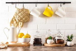 fondo de cocina elegante parte de una cocina moderna. una jarra blanca, un tazón de limones, frascos de vidrio llenos y plantas de interior en macetas.