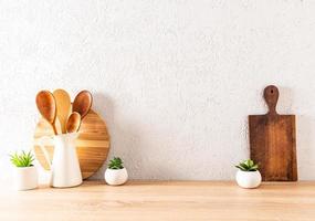 fondo de cocina moderno con utensilios en una encimera de madera contra la pared texturizada. espacio para texto. artículos ecológicos. foto