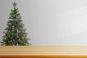 an empty wooden table with a Christmas tree background in the living room photo