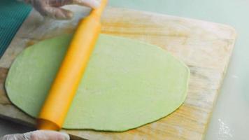 The chef spreads the green dough with a rolling pin. Tortillas prepared and decorated with spinach and beets. Red and green tortillas video