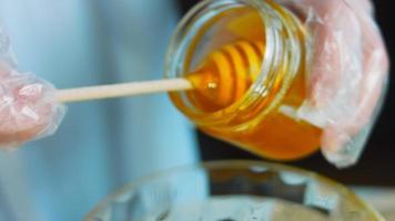 The cook pours honey into the transparent bowl. Use a wooden spoon for honey video