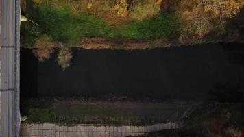 Aerial top down view of a river bridge and autumn forest with cabin