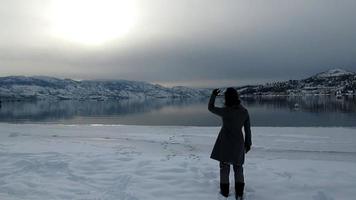 lady walking by snow lake mountain video
