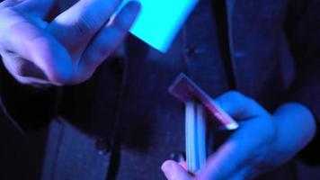 Close-up, Hands of a Magician Performing Tricks with a Deck of Cards. Blue Lighting. Conjurer Shows Focus. Unrecognizable person. video