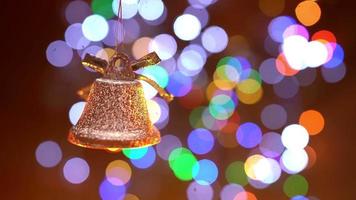 campana de Navidad sobre un fondo borroso de guirnaldas brillantes. celebración de Año Nuevo. de cerca. video