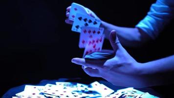 gros plan, mains d'un magicien exécutant des tours avec un jeu de cartes. éclairage bleu. le prestidigitateur montre la concentration. la caméra tourne rapidement à 360 degrés. video