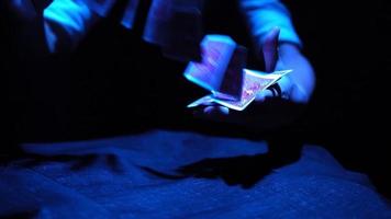 Close-up, Hands of a Magician Performing Tricks with a Deck of Cards. Blue Lighting. Conjurer Shows Focus. Camera Quickly Rotates 360 Degrees. video