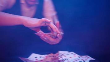 primer plano, manos de un mago que realiza trucos con una baraja de cartas. iluminación azul. el prestidigitador muestra el enfoque. la cámara gira rápidamente 360 grados. video