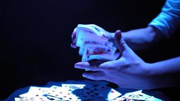Nahaufnahme, Hände eines Zauberers, der Tricks mit einem Kartenspiel vorführt. blaue Beleuchtung. Beschwörer zeigt Fokus. Kamera dreht sich schnell um 360 Grad.