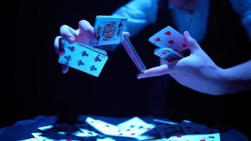 close-up, mãos de um mágico realizando truques com um baralho de cartas. iluminação azul. mágico mostra foco. câmera gira rapidamente 360 graus. video