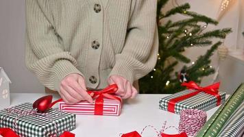 mujer irreconocible envolviendo regalos de navidad. imágenes festivas en colores tradicionales. video