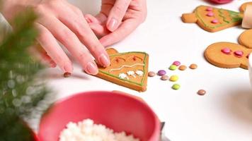 filmagem com mulher decorando biscoitos de gengibre. clima de férias de natal e ano novo. close-up vista da mesa da cozinha em preparação video