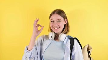 jovem mulher caucasiana mostrando sinal de mão ok retrato de estúdio em fundo amarelo video