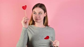 glimlachen blond vrouw met harten tegen roze achtergrond. st Valentijnsdag studio portret video