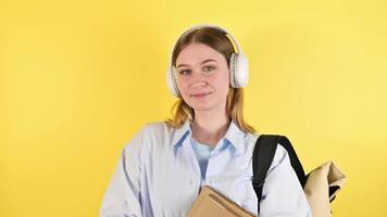 Happy female student lin headphones holding books High school or university education.Educational courses concept video