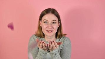 Studio footage of a young happy female blowing heart shaped confetti. St Valentine's day concept video