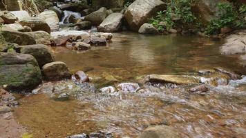 Wasser, das flussabwärts in der Nähe eines Wasserfalls voller Felsen in der Natur fließt video