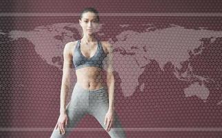 Digital world map on picture. Young woman with slim body shape in sportswear have fitness day indoors photo