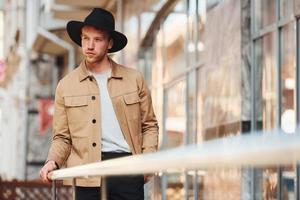 Elegant young man in black hat and formal classy clothes outdoors in the city photo