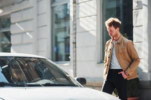 Walks to his car. Elegant young man in formal classy clothes outdoors in the city photo