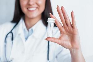 Holding drugs in hand. Young nurse indoors in modern clinic. Conception of healthcare photo