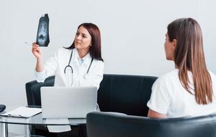 Shows results of x-ray. Young woman have a visit with female doctor in modern clinic photo