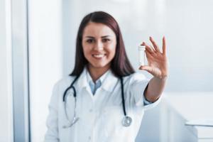 Holding drugs in hand. Young nurse indoors in modern clinic. Conception of healthcare photo