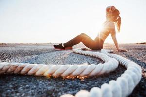 mujer en ropa deportiva sentada con nudos en la carretera al atardecer foto