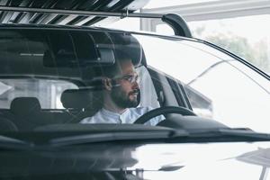 Young handsome man in formal clothes sitting in brand new automobile photo