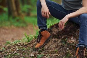 Close up view of man's legs on the rock in forest. Traveler have a walk photo