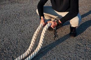 Man in sportswear sitting on the road at evening time with ropes and resting photo