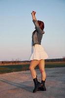 Redhead woman in skirt standing and posing for a camera on the road at evening time photo