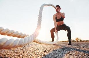 Woman in sportswear training with knots on the road at evening time photo