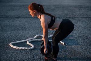 levantando pesas. mujer en ropa deportiva tiene un día de fitness en la carretera por la noche foto