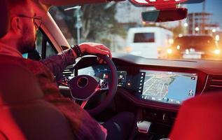 Handsome unshaved man in fashionable clothes riding his automobile photo