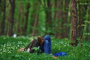 Couple lying down on the grass in forest together at daytime photo